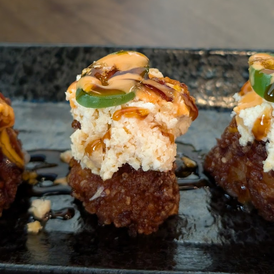 Close-up of Hanamaru Sushi's crispy rice topped with spicy tuna, jalapeño, and sauce.